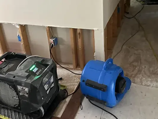 Air mover and dehumidifier drying flood-cut drywall in a room