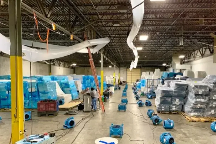 Air movers and dehumidifiers drying a large commercial warehouse floor