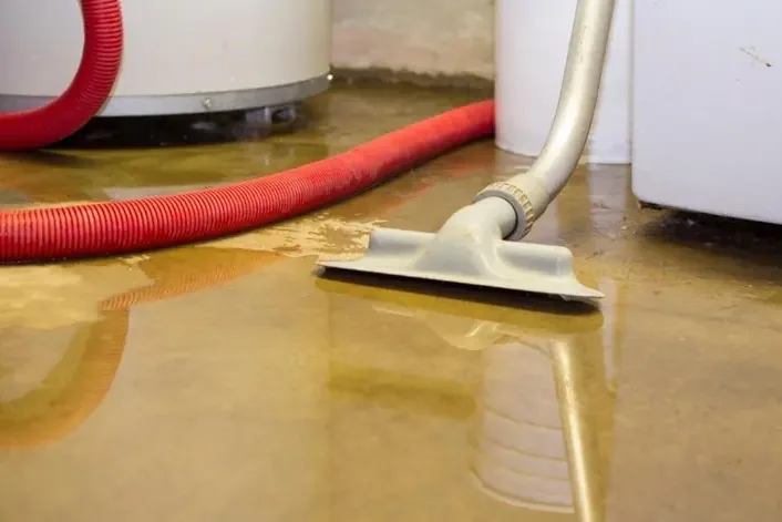 Wet vacuum pulling water off the floor around a leaking water heater